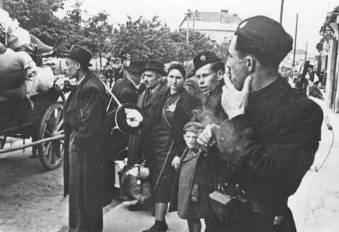 Slovak militia standing next to Jews, before the latter were deported from Slovakia along with their personal effects, 1942.