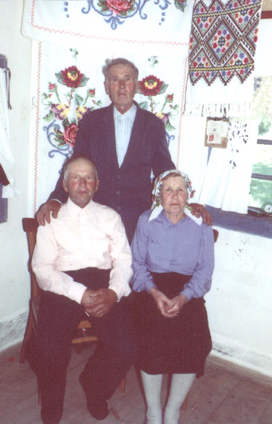Nikolay and Maria Oshurko sitting, their son Yakov is standing behind