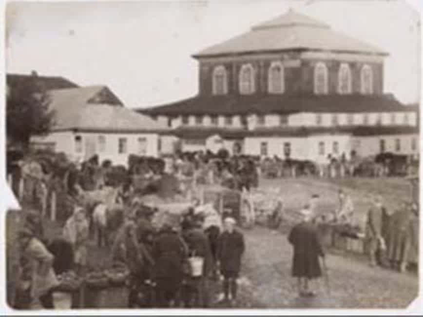 A market day in the 1920s. The multi-story building is the synagogue of the town