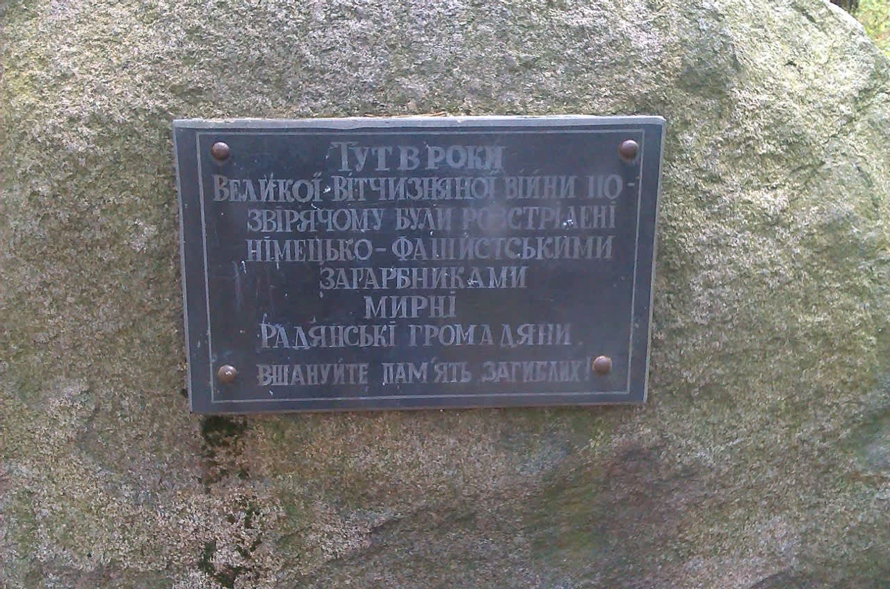 A black marble plaque with a Ukrainian-language inscription upon the monument.